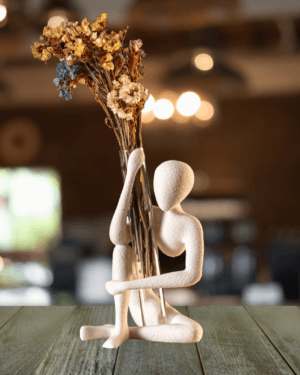 Sitting figurine vase holder – white minimalist human sculpture holding transparent bud vase with dried flowers